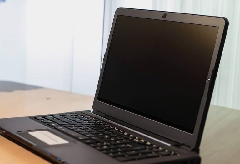 Un ordinateur portable éteint posé sur une table en bois.